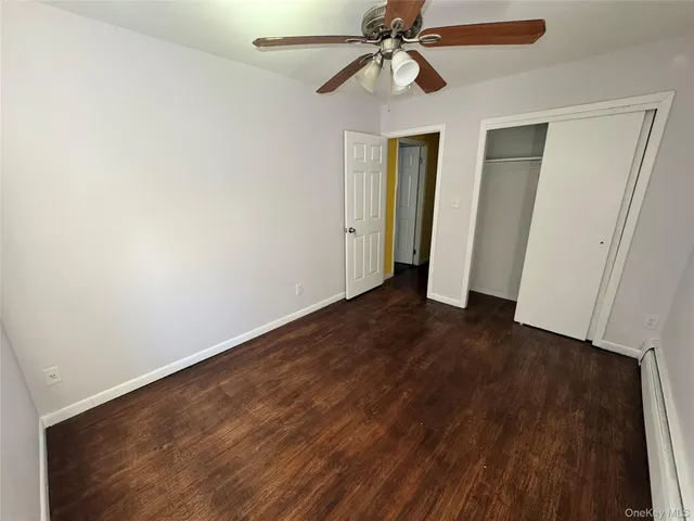 an empty room with wooden floor closet and fan