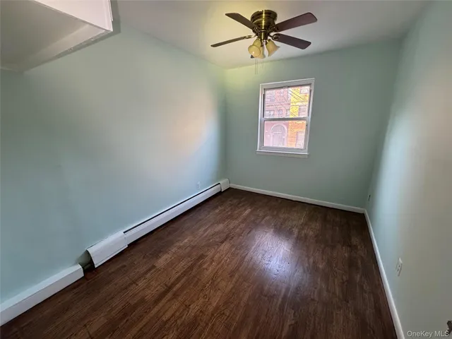 an empty room with wooden floor chandelier fan and windows
