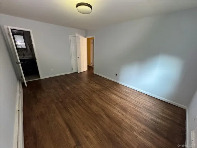 an empty room with wooden floor and mirror