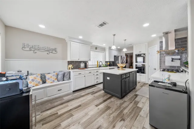 a kitchen with stainless steel appliances kitchen island granite countertop a refrigerator cabinets and wooden floor