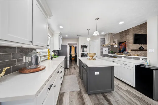a kitchen with kitchen island granite countertop a sink a counter top space stainless steel appliances and cabinets