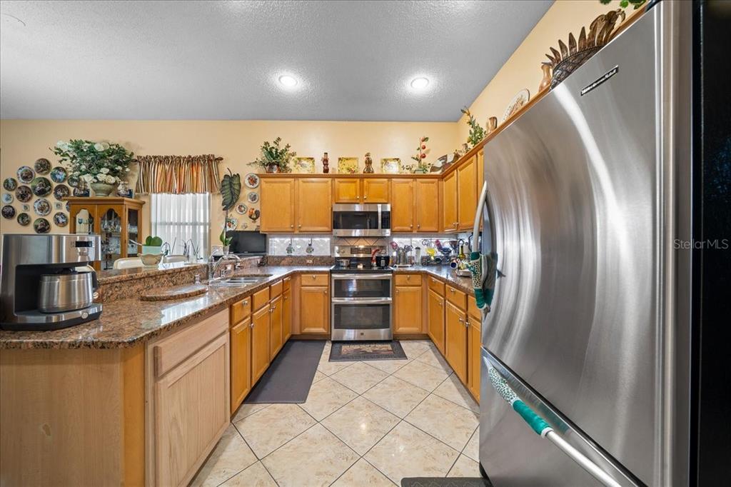 1010 Raining Meadows Lane Orlando, FL 32824 - Photo 13 of 57 a kitchen with stainless steel appliances granite countertop a refrigerator a sink and a stove