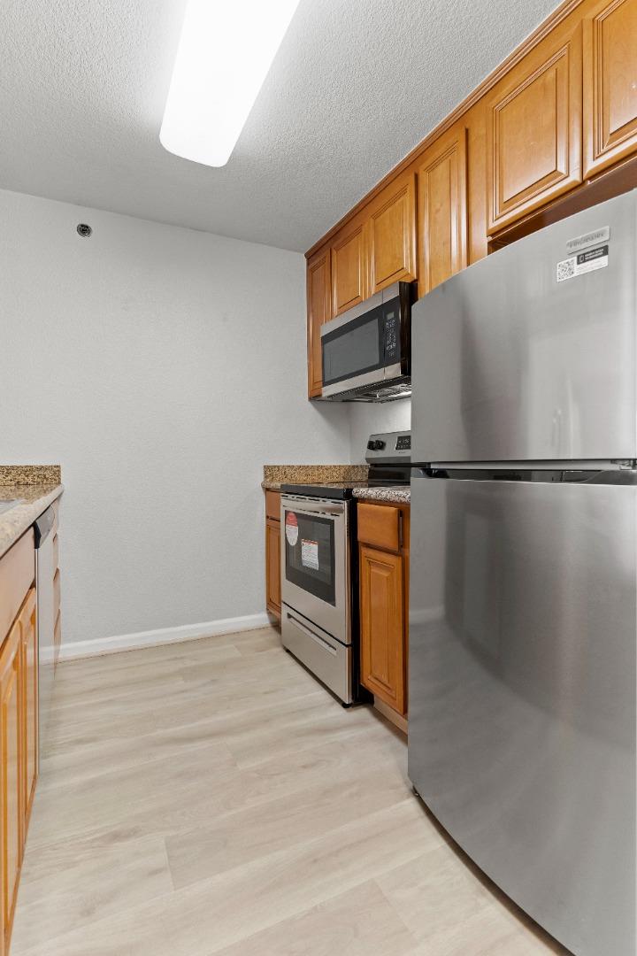 29581 Highgate Drive, Unit 219 Hayward, CA 94544 - Photo 7 of 24 a kitchen with stainless steel appliances granite countertop a refrigerator a stove a sink and a microwave