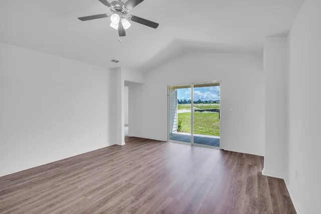 a view of an empty room with window and wooden floor