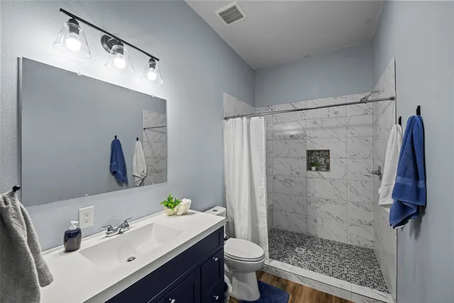 a bathroom with a sink vanity granite toilet and shower