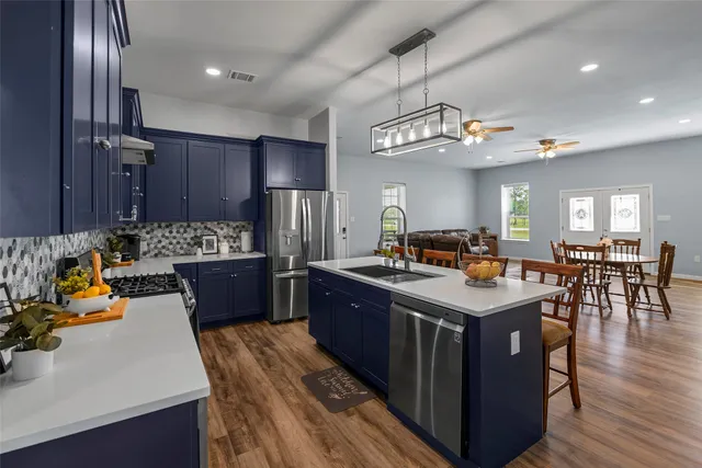 a kitchen with stainless steel appliances granite countertop a sink a stove and a refrigerator
