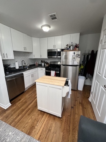 Undisclosed Address Chicago, IL 60657 - Photo 4 of 9 a kitchen with kitchen island wooden floors white appliances and sink