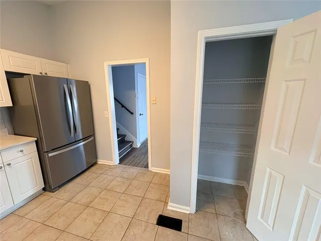 a view of a refrigerator in kitchen and an empty room in wooden floor