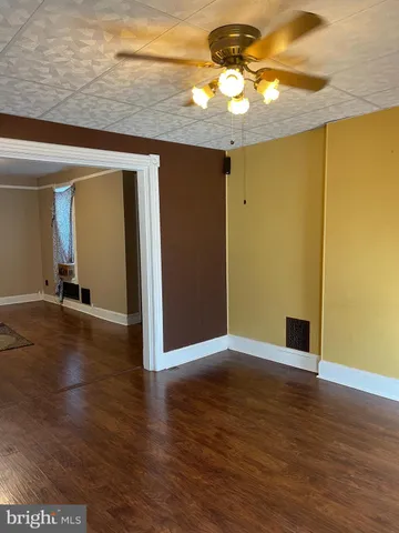 an empty room with wooden floor and chandelier fan