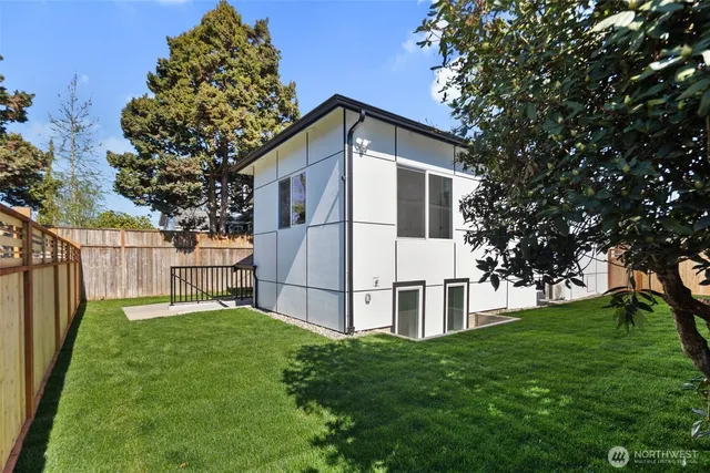 a view of backyard with wooden fence and large trees