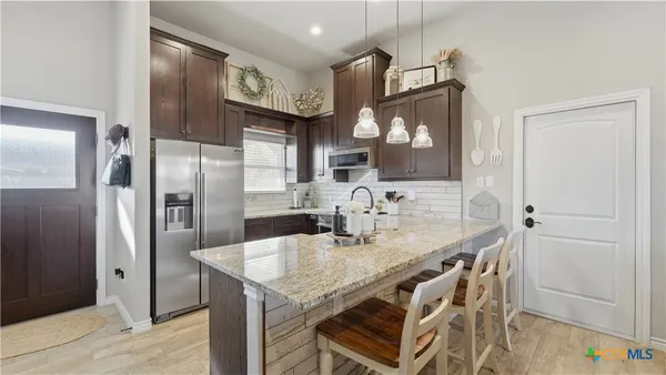 a kitchen with stainless steel appliances granite countertop a kitchen island a stove a refrigerator and a cabinets