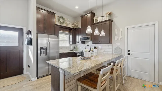 a kitchen with stainless steel appliances granite countertop a kitchen island a stove a refrigerator and a cabinets