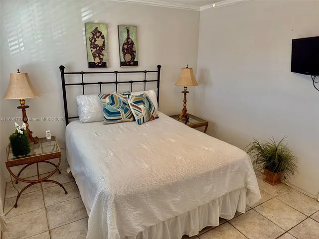 a bedroom with a bed and a potted plant on dresser