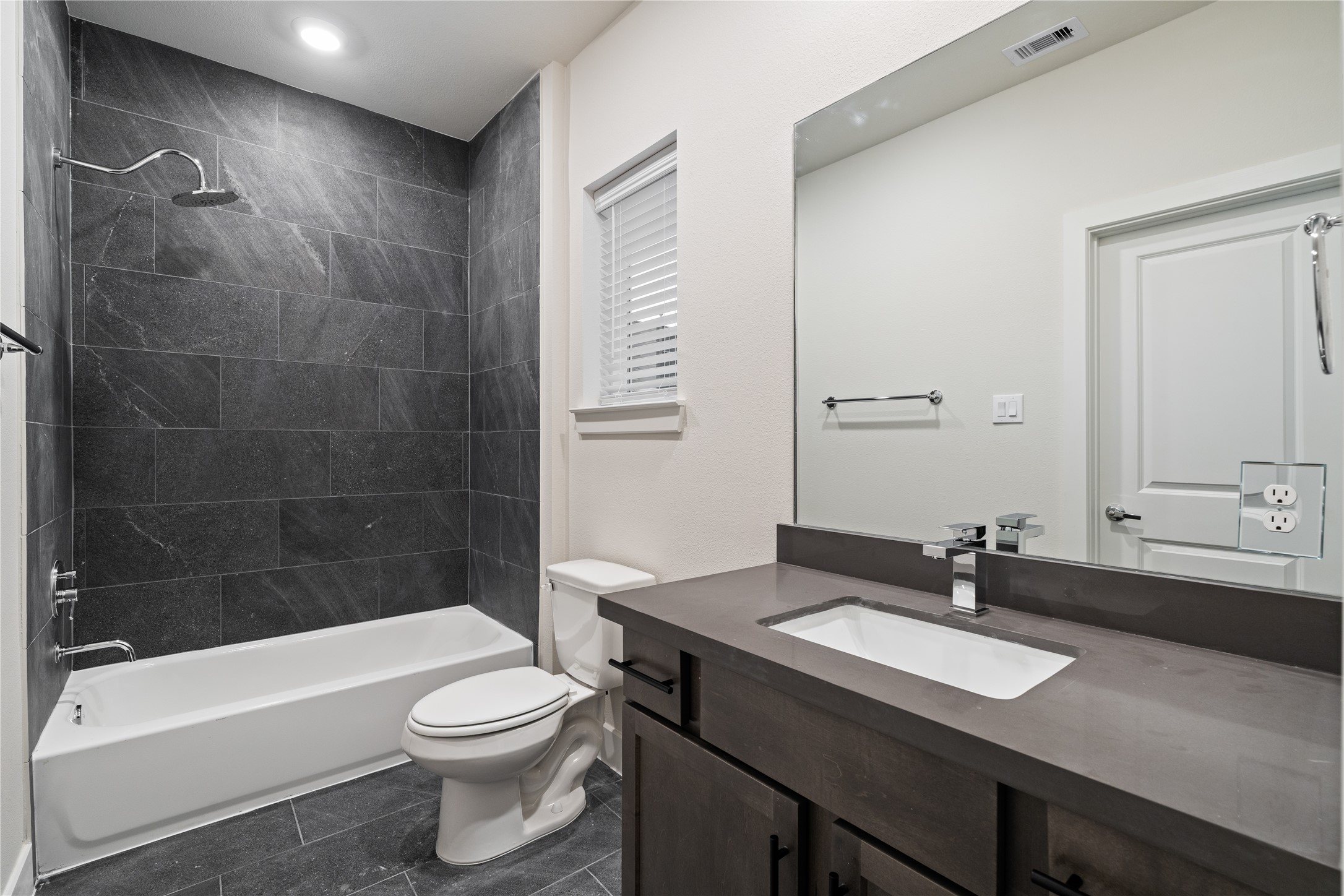 6445 Rena Street Houston, TX 77092 - Photo 27 of 33 Secondary bathroom finished with full height dark tile surround and a clean, modern vanity.