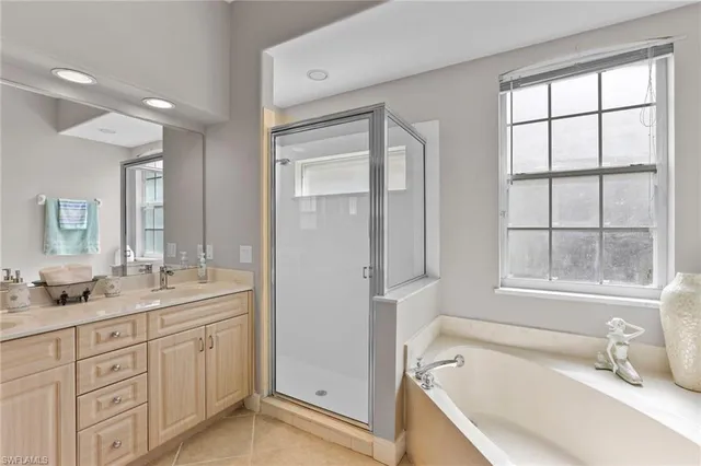 a bathroom with a tub sink double vanity and windows