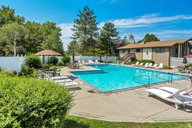 6907 South 745th Street East, Unit G Midvale, UT 84047 - Photo 28 of 30 Expansive pool area with large swimming pool, multiple loungers, and privacy fencing