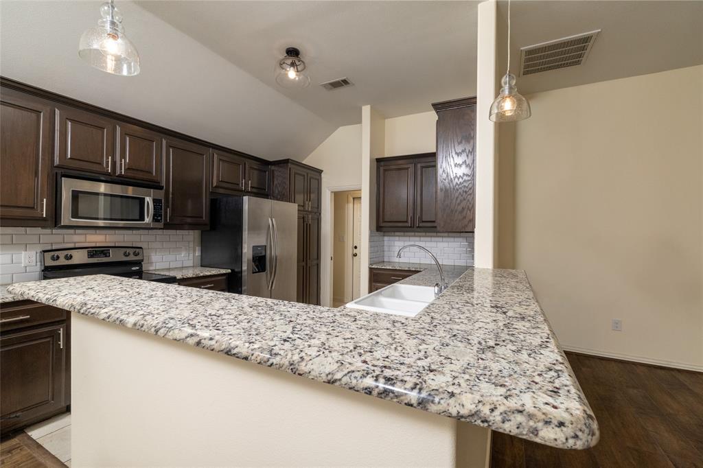 405 Kimbrough Road Azle, TX 76020 - Photo 11 of 39 a kitchen with kitchen island granite countertop a sink refrigerator and microwave