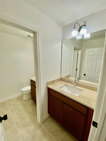 a bathroom with a granite countertop sink a toilet and a mirror