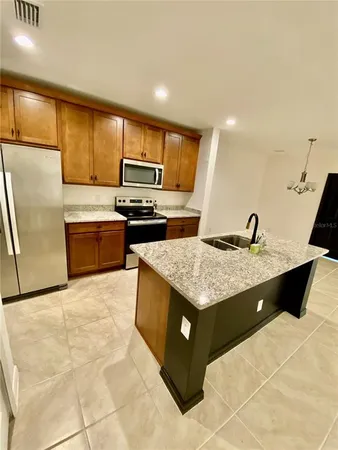a kitchen with stainless steel appliances kitchen island granite countertop a sink and a refrigerator