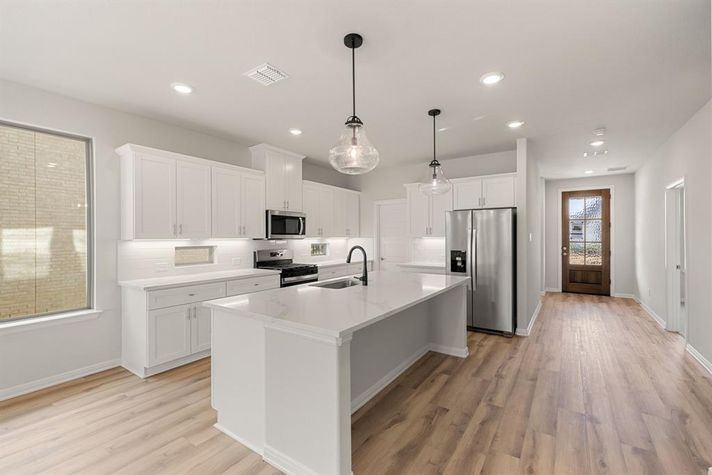 1847 Cole Road Van Alstyne, TX 75495 - Photo 6 of 26 a kitchen with stainless steel appliances a stove top oven a refrigerator a sink and white cabinets with wooden floor
