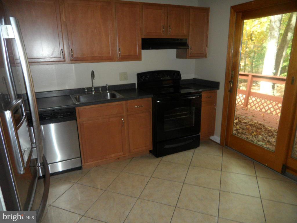 9485 Good Lion Road Columbia, MD 21045 - Photo 2 of 20 a kitchen with granite countertop a refrigerator and a stove top oven