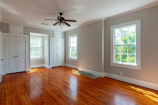 a view of an empty room with wooden floor and a window
