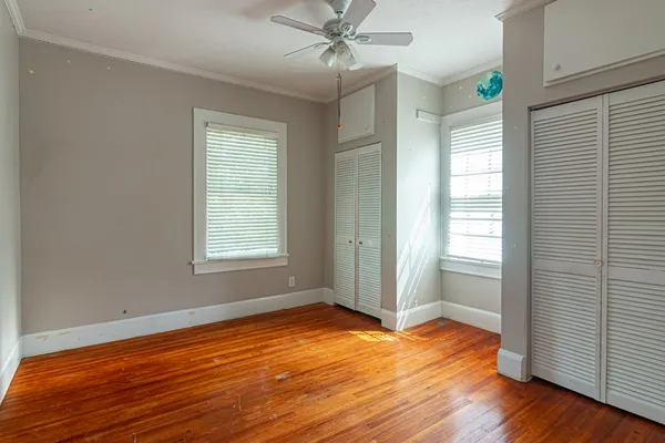 an empty room with wooden floor and windows