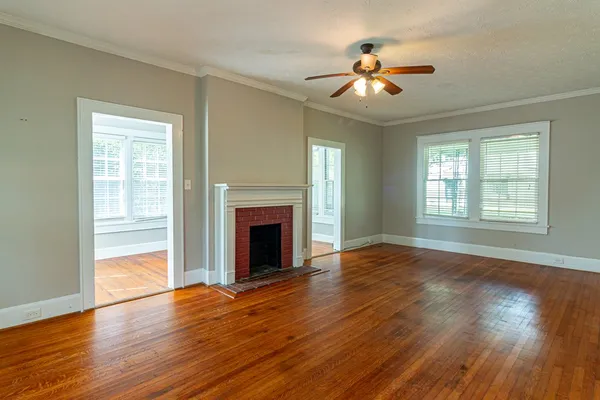 a view of an empty room with wooden floor fireplace and a window