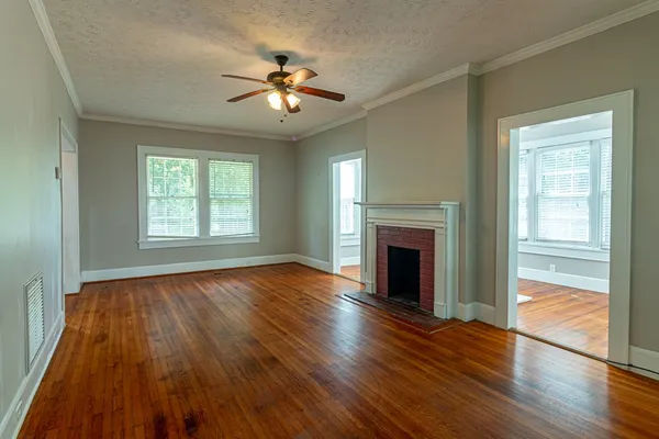 a view of an empty room with wooden floor fireplace and a window