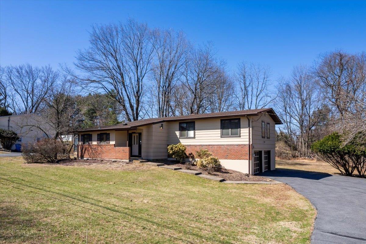 Single story home with aphalt driveway, brick siding, and a front yard