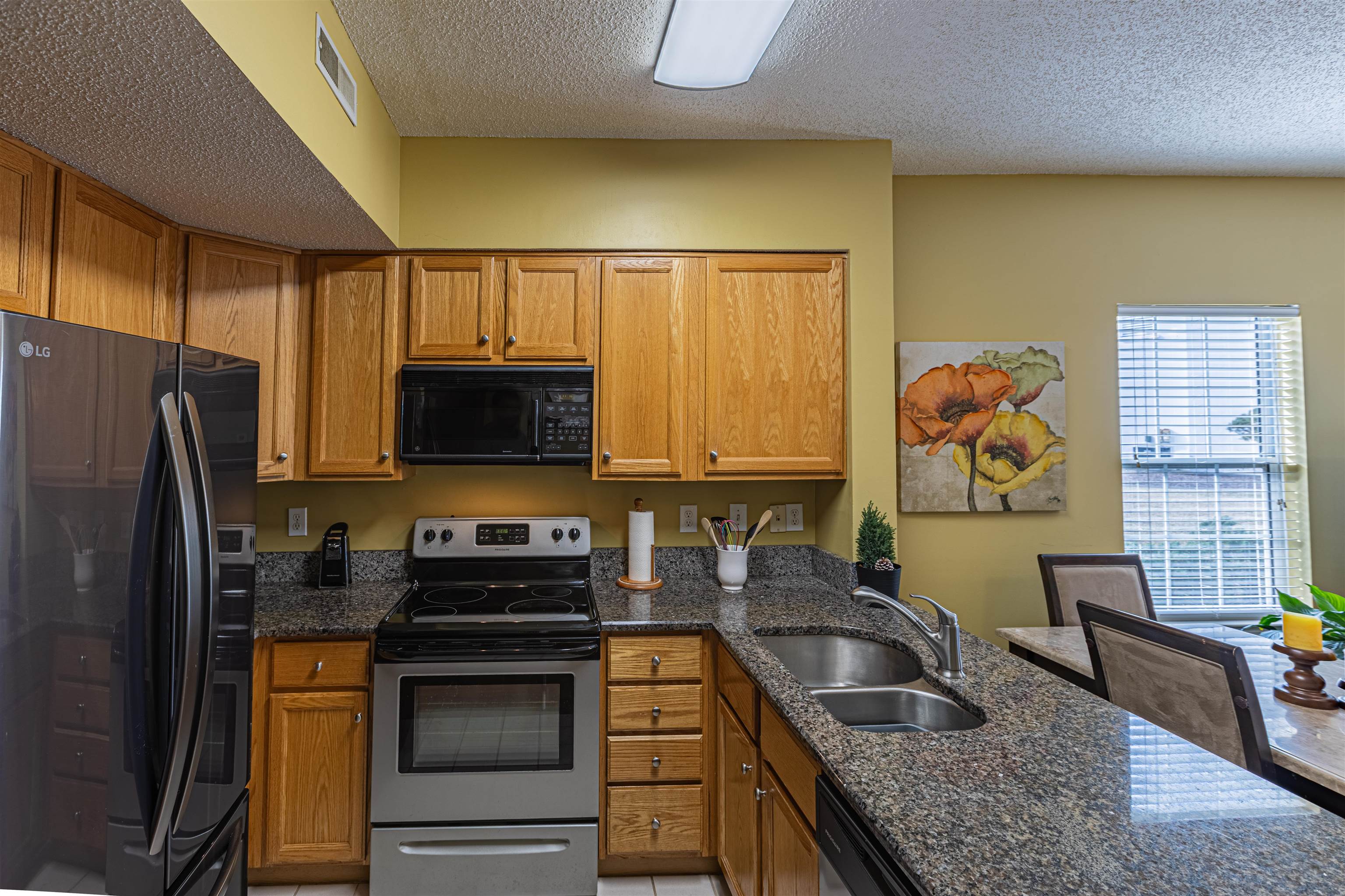 4603 Arran Court, Unit A Myrtle Beach, SC 29579 - Photo 3 of 32 Kitchen with black appliances, dark stone countertops, brown cabinets, a textured ceiling, and a peninsula