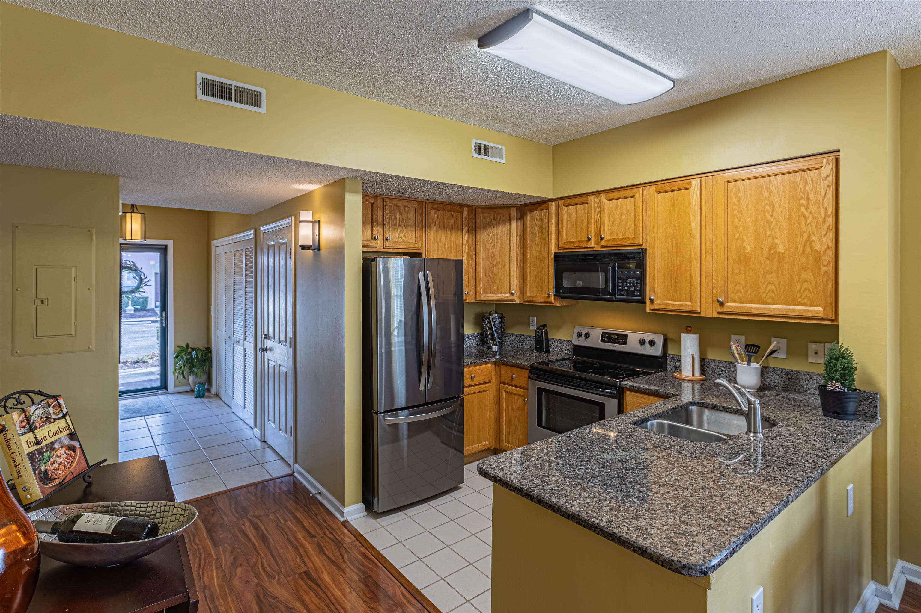 4603 Arran Court, Unit A Myrtle Beach, SC 29579 - Photo 4 of 32 Kitchen featuring dark stone countertops, stainless steel appliances, a textured ceiling, light wood-style floors, and brown cabinets