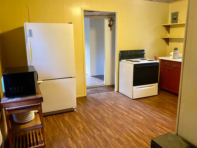a view of a kitchen with a stove fridge and wooden floor