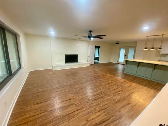 a view of an empty room with window and wooden floor