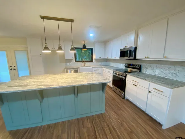 a kitchen with stainless steel appliances kitchen island granite countertop a sink a stove and cabinets