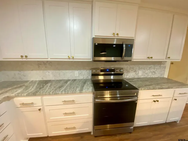 a kitchen with granite countertop a stove and a microwave