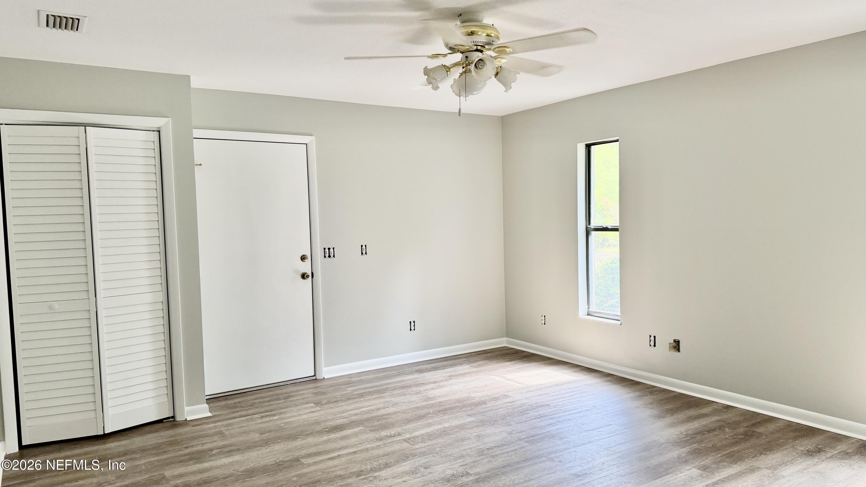 850 Cousintown Road Interlachen, FL 32148 - Photo 10 of 27 an empty room with wooden floor and windows