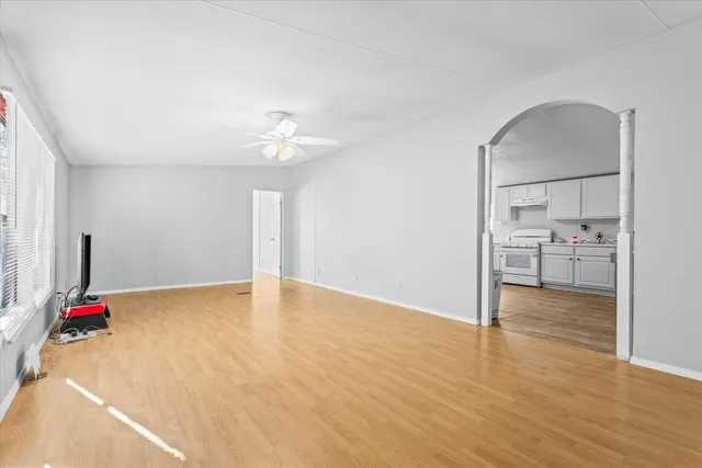 a view of an empty room with kitchen and a window