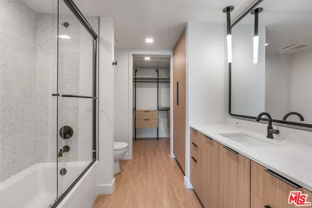a bathroom with a double vanity sink a toilet and shower