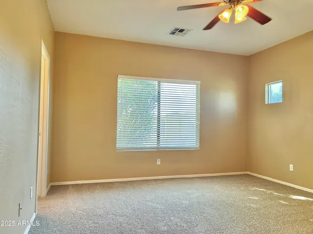 an empty room with a window and a fan
