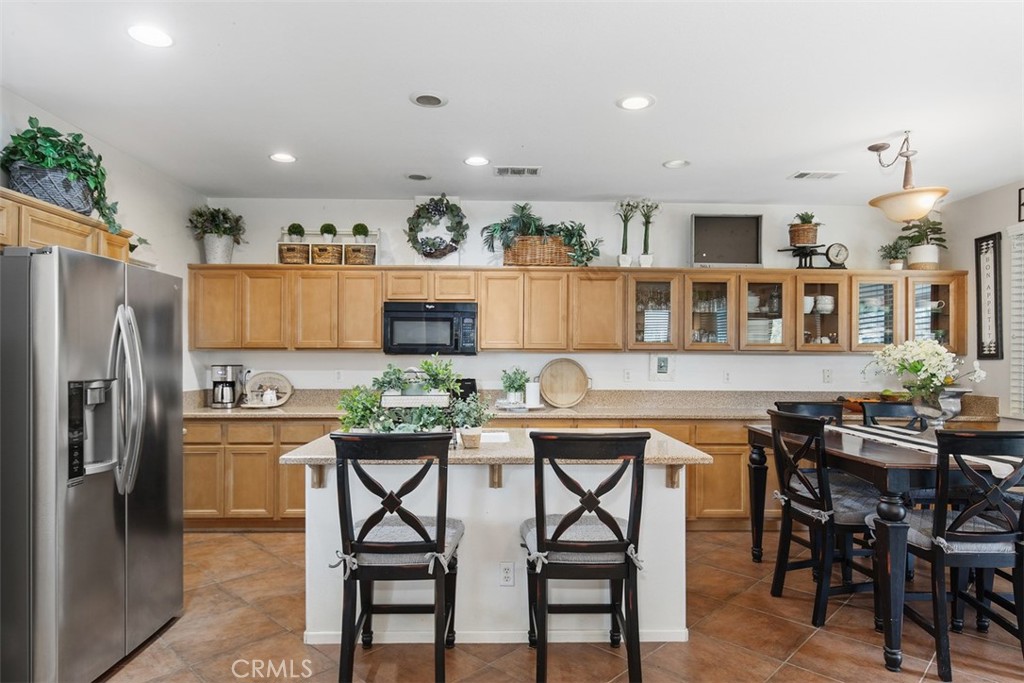 32095 Zion Way Winchester, CA 92596 - Photo 14 of 30 a kitchen with stainless steel appliances kitchen island granite countertop a dining table chairs and a refrigerator