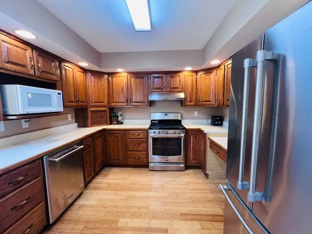 a kitchen with stainless steel appliances granite countertop a refrigerator stove a sink dishwasher and wooden cabinets
