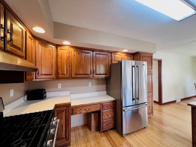 a kitchen with stainless steel appliances a refrigerator a sink a stove a microwave and wooden floors