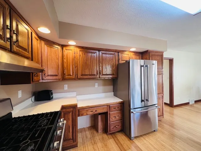 a kitchen with stainless steel appliances granite countertop a refrigerator a stove and a sink with wooden floor