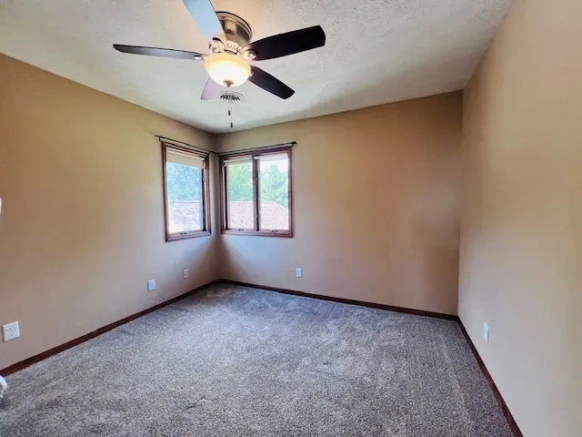 an empty room with windows and fan