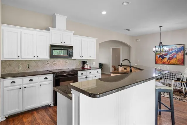 a kitchen with granite countertop a sink stove and cabinets
