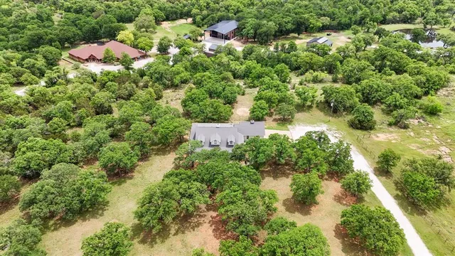 an aerial view of residential house with outdoor space and trees all around