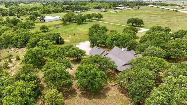 an aerial view of residential houses with outdoor space and trees all around