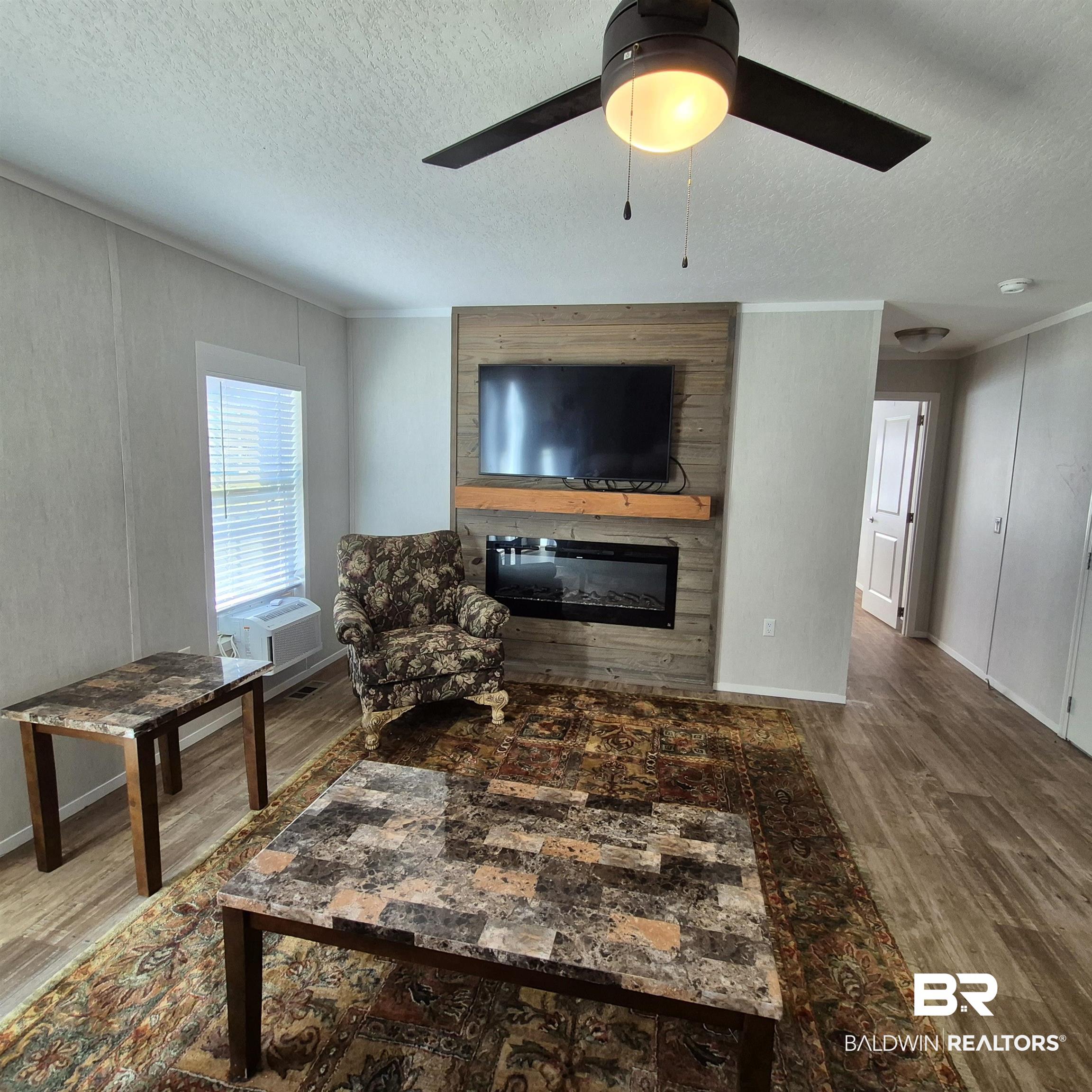 8867 Old Stage Road Repton, AL 36475 - Photo 4 of 37 Living room with a glass covered fireplace, wood finished floors, a textured ceiling, ceiling fan, and ornamental molding