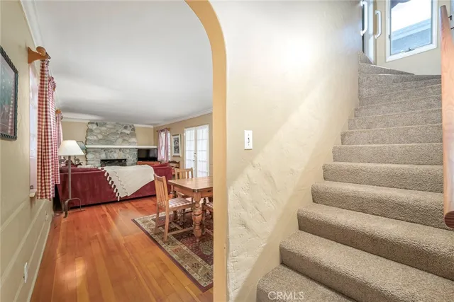 a living room with couches and kitchen view with wooden floor